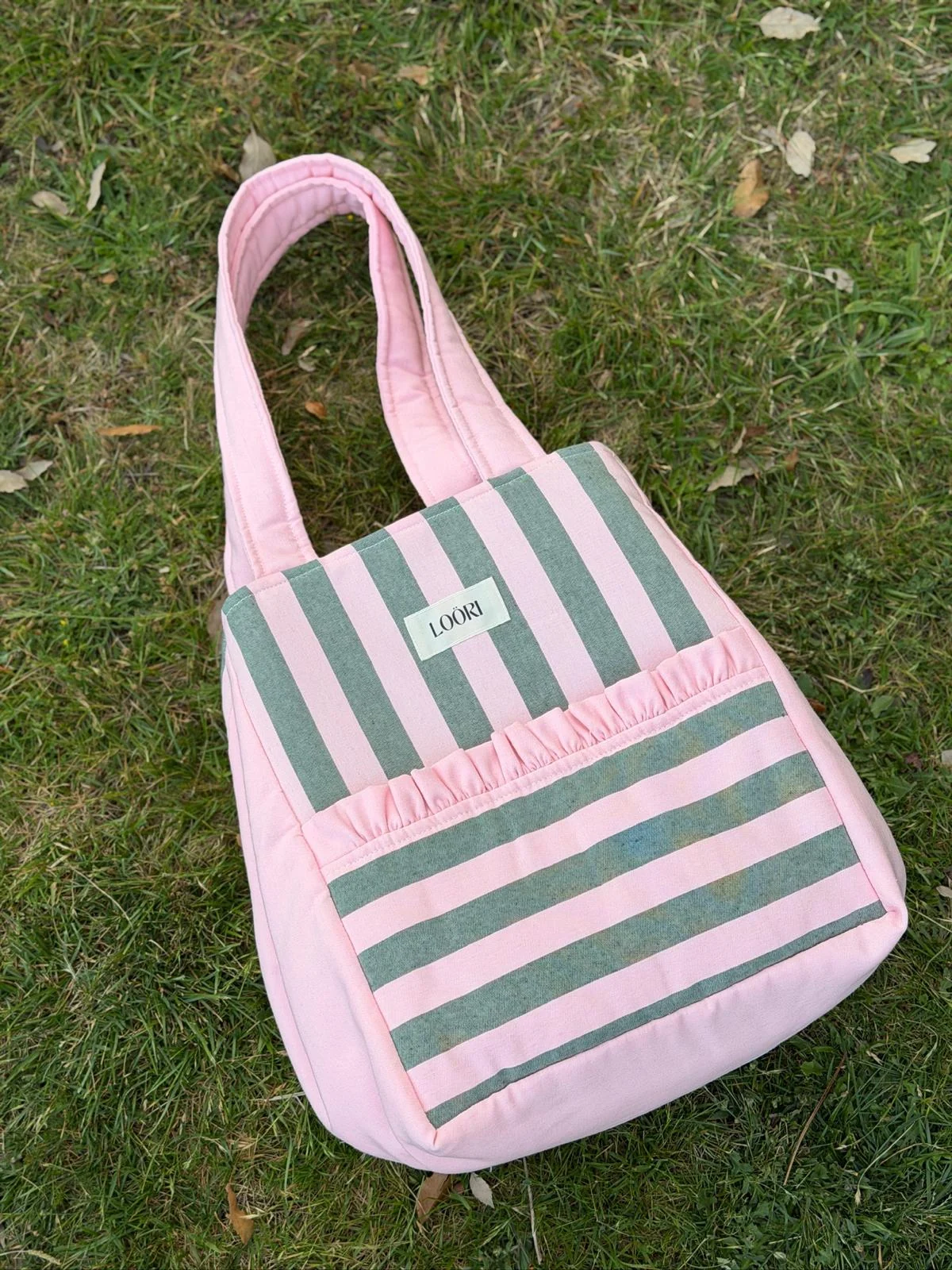 Bolso LOÖRI de rayas rosa y verde sobre la hierba