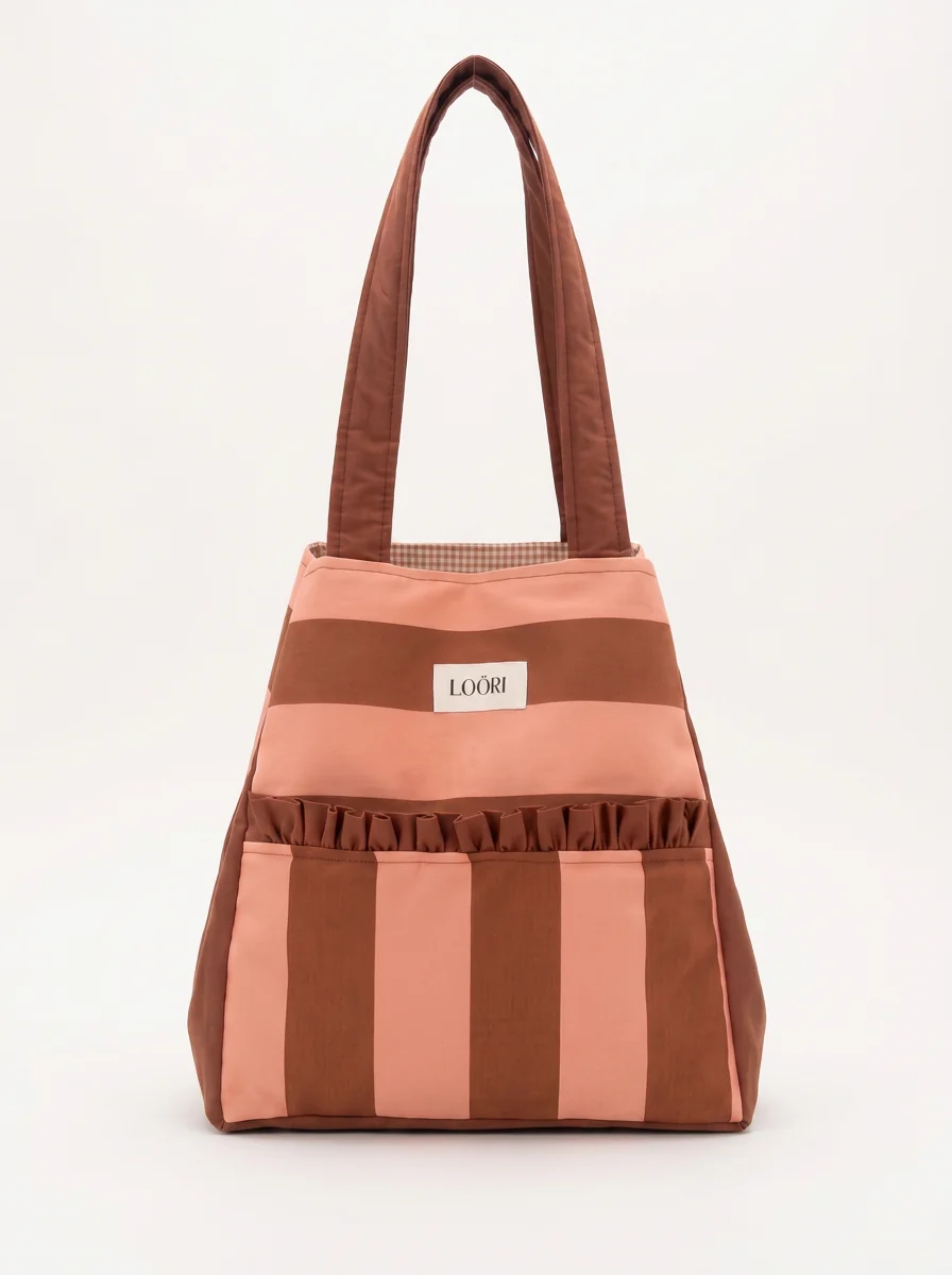 Bolso LOÖRI TERRA de rayas en salmón y marrón sobre fondo blanco de estudio