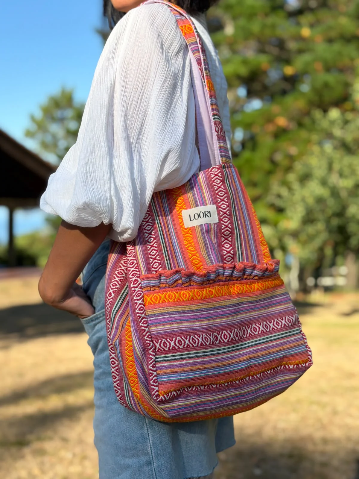 Mujer llevando al hombro el bolso LOÖRI CARMELA en un parque
